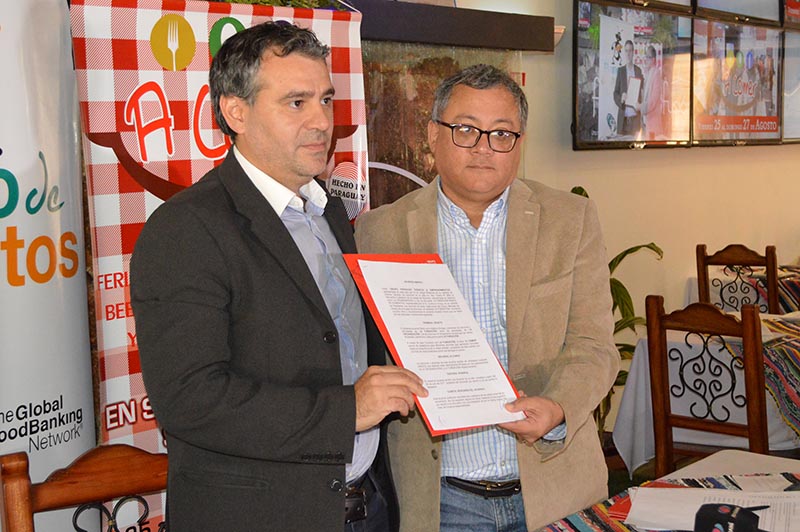 Fanego y Robinson exhiben el convenido firmado para que el Banco de Alimentos pueda cumplir sus fines durante la Feria A Comer.
