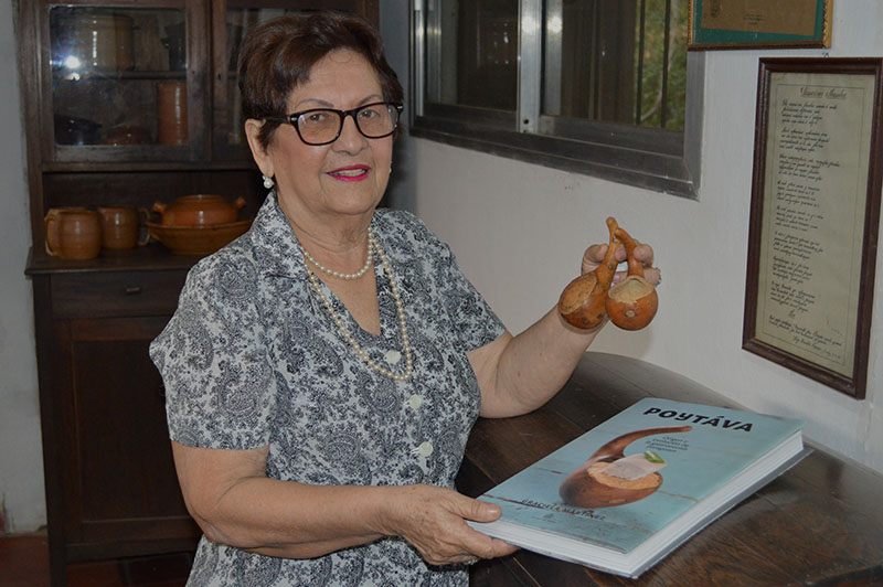 Graciela Martínez en una de manos exhibe su libro Poytáva y en la otra sostiene un utensilio utilizado por nuestros ancestros.
