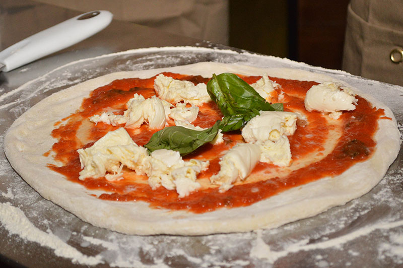 Pizza al estilo napolitano. Ingredientes sencillos, masa, salsa de tomate, queso y albahaca. La masa tiene un leudado de 24 horas, está estirada a mano rústicamente.