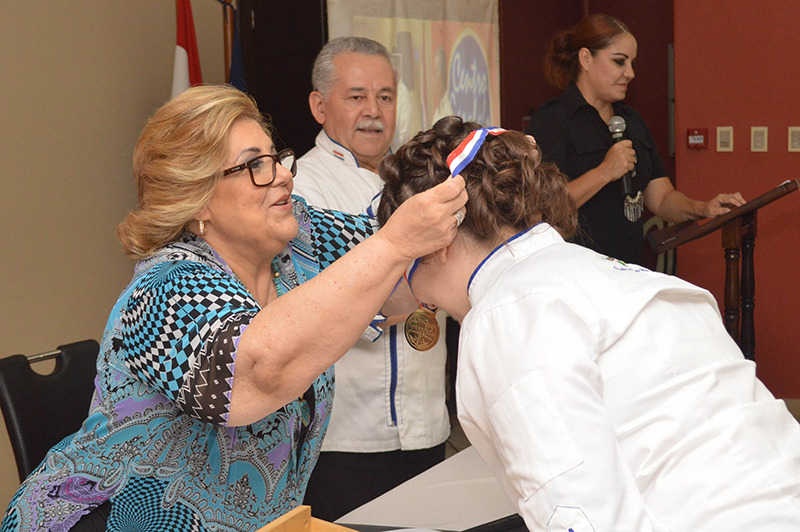 Sarita Garofalo entregando una medalla a una de las ganadoras del Concurso de Cocina María Clara Benza de Garofalo, que cada año realiza la institución.