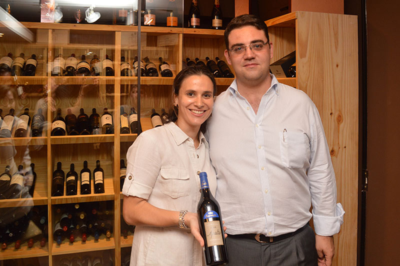 Bettina Torres y Jean-Philippe Bierre, el matrimonio propietario de Le Parisienne. Ella mostrando uno de los mejores vinos de la vinoteca. Atrás se ve el espacio especial destinado de las etiquetas Premium.