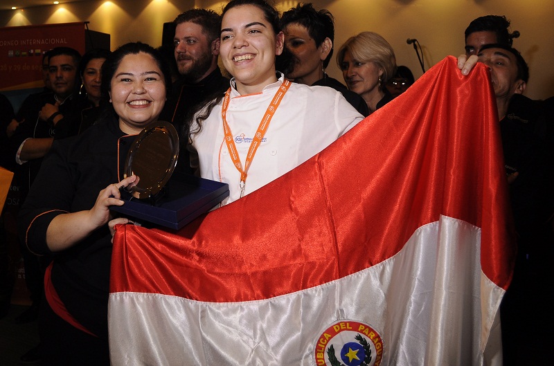 Jessica Fariña Rojas, a la derecha, aparece junto a su profesora y tutora Marlene Grance, tras recibir el primer premio en el concuro Inter Igi realizado en Rosario, Argentina.