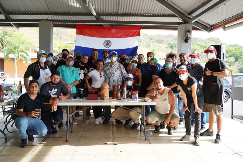 La típica foto grupal. Leyzman Salin, centro con chaqueta estampada, aparece junto a sus alumnos, con el fondo de la bandera paraguaya.