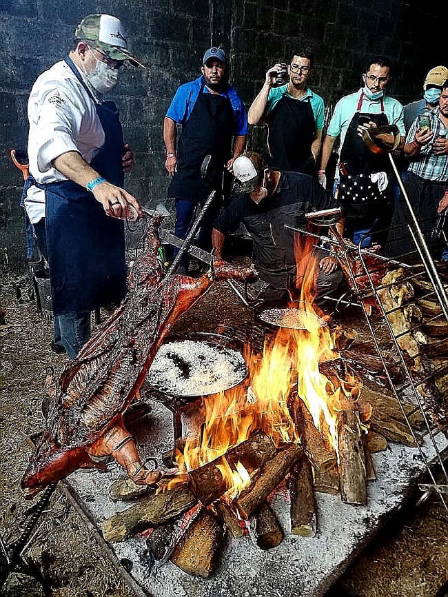 Frente al fogón, Leyzman Salin dando sus explicaciones sobre como hacer un asado. Dictó varios cursos en México y Costa Rica, hablando del asado paraguayo.