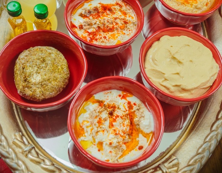 La foto muestra una trilogía de purés. El de berenjena, el de garbanzo y la cuajada con aceite de oliva. A la izquierda, el de aspecto sólido es un queso árabe: Shanklish.