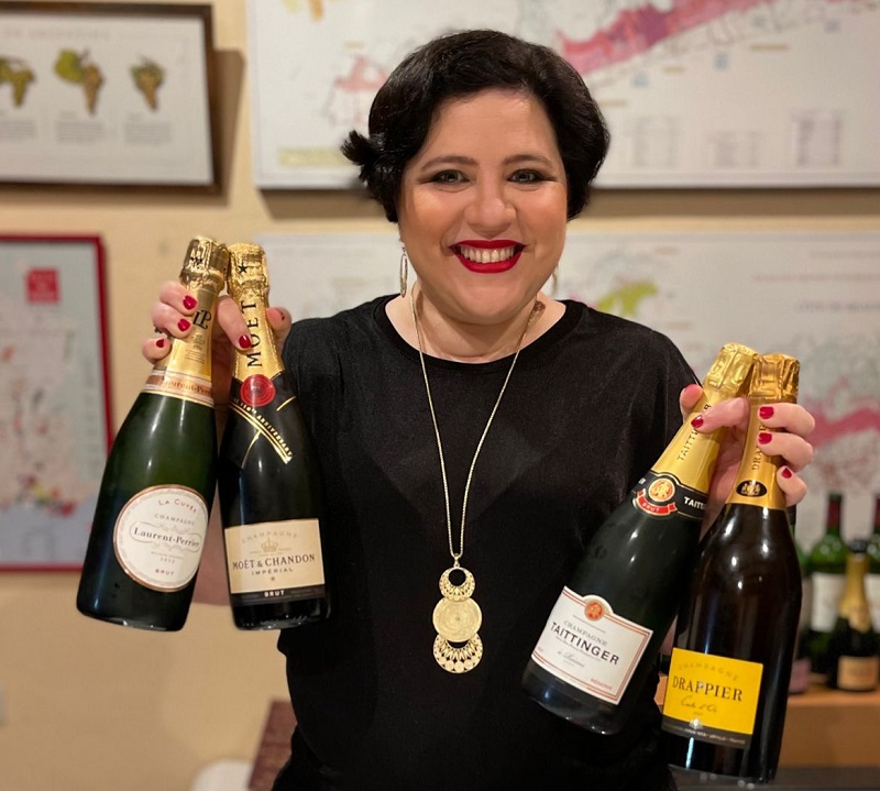 Gaby Fines exhibiendo las botellas de champagne que fueron degustadas durante una reciente cata a ciegas.
