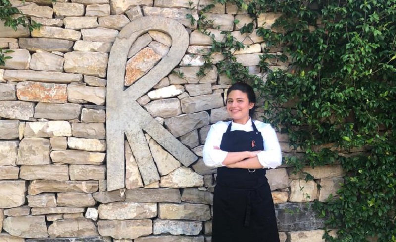 Julieta posando frente al restaurante Mas Marroch con el logotipo del Grupo Roca.